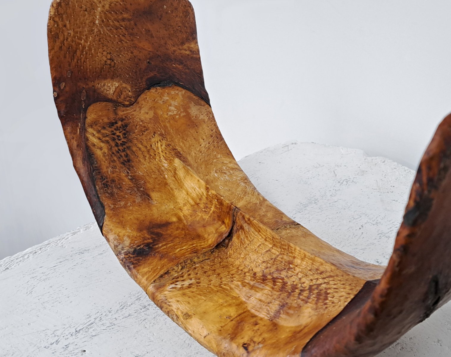 Curved sculpture, brown chicken skin surface.