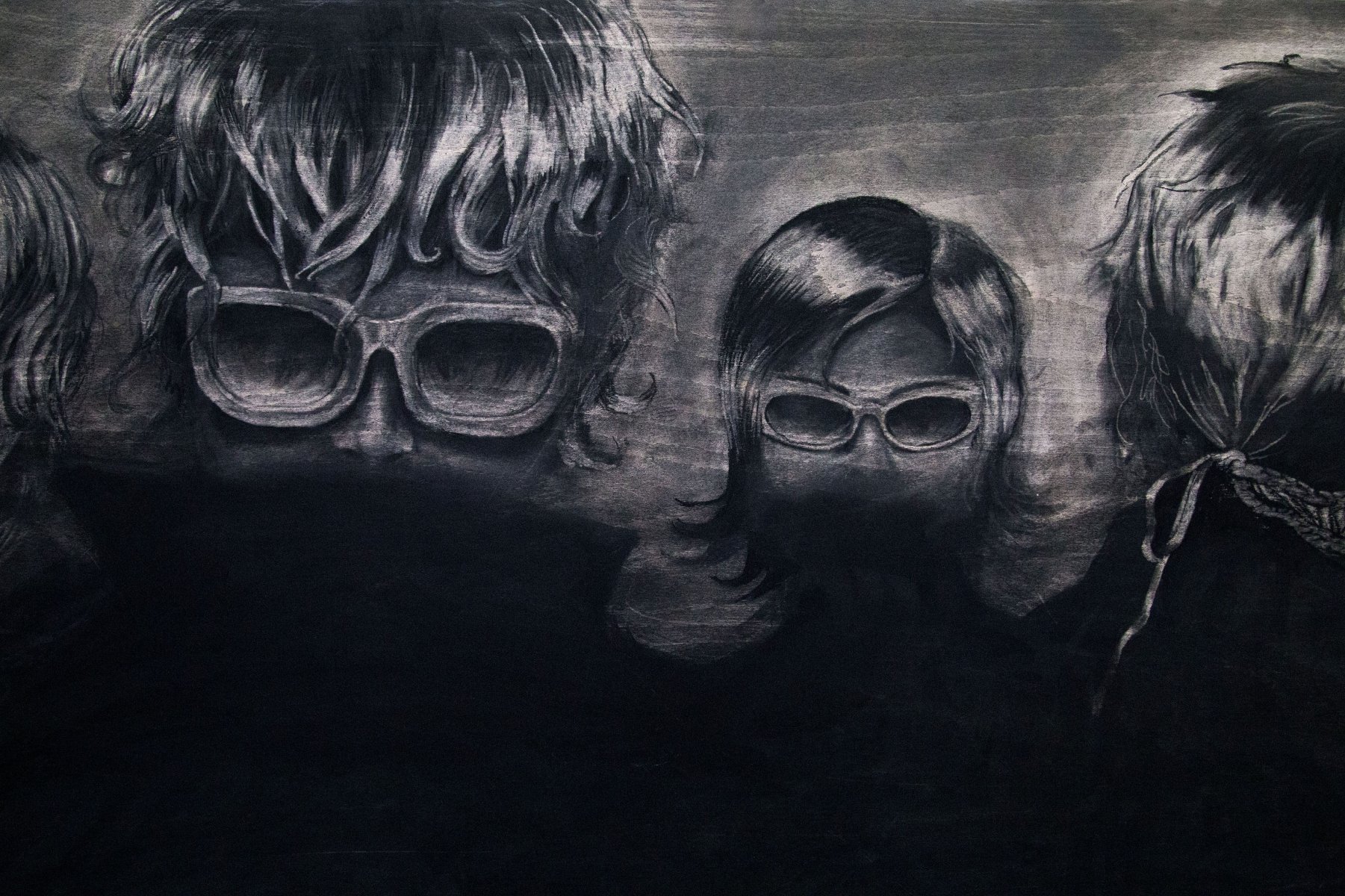 Charcoal drawing of three heads, two wearing glasses