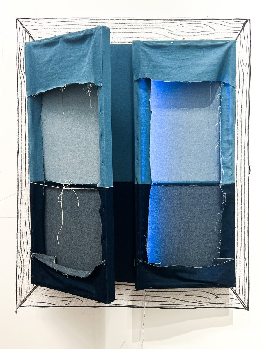 This work is a triptych piece that is made up of three canvas’ of two shades of blue denim. The canvas’ are hinged together and fold mostly inwards. The inward folding of the canvas shows the back of the denim that has been sewn and stapled. On the left-hand side is a piece of string rapped around the dividing line of the denim. On the right-hand side is a LED strip light lighting up a line of the denim. Around the piece is a charcoal drawing of a wooden frame directly onto a white wall.